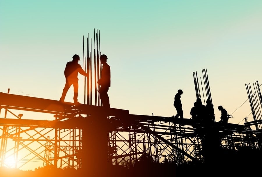 Imagery of men during an early morning golden hour placing rebar at a construction site.